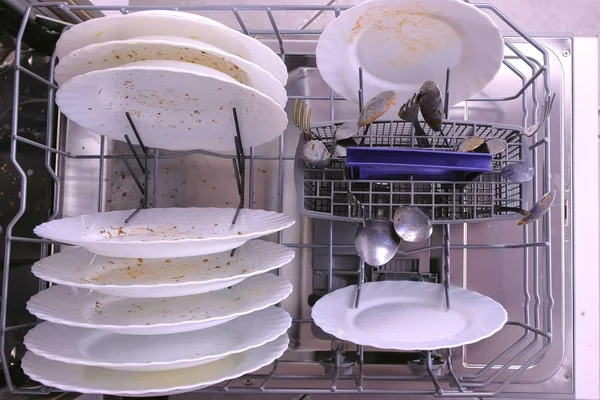 Placas sujas brancas e colher na cesta da máquina de lavar louça . — Fotografia de Stock