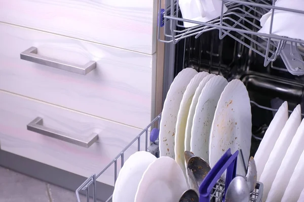 Брудний білий посуд і столові прибори в посудомийних кошиках на кухні . — стокове фото