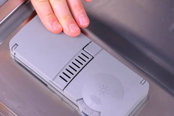 Mans mano sta mettendo tablet detergente nel vano automatico in lavastoviglie . — Foto Stock