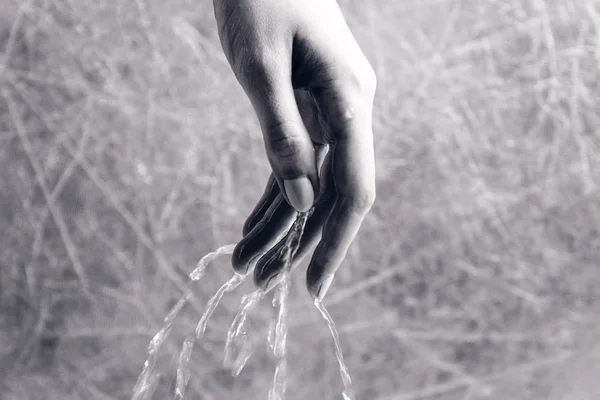 여성의 손을 통해 물이 쏟아지고 있습니다. 손 클로즈업. — 스톡 사진