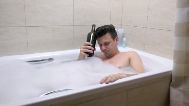 Erwachsener müder Mann der 30er schläft mit Flasche Rotwein im Bad.