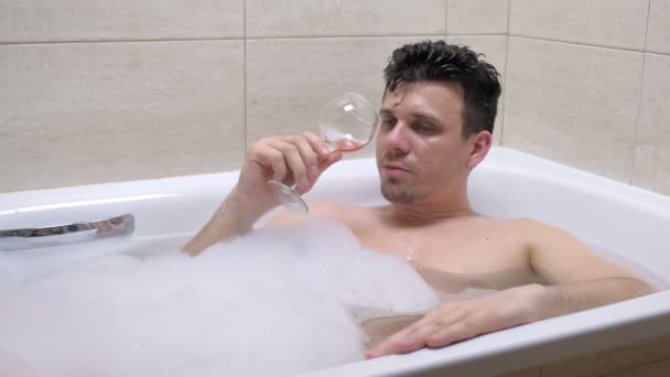 Drunk man is drinking red wine and falling asleep in bath. — Stock Video