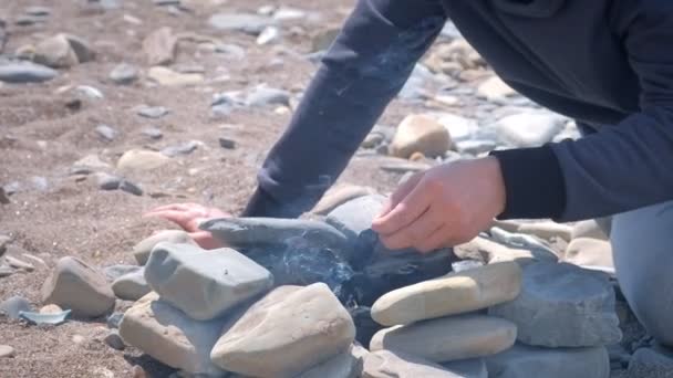 Dad and son are igniting the coals in the bonfire on the stones brazier with wooden sticks. — Stock Video