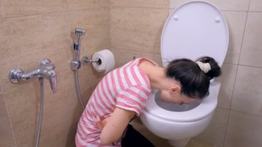 Hasta genç kadın evde yerde otururken tuvalette kusuyor, gıda zehirlenmesi belirtisi.
