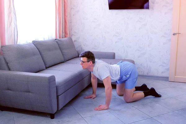 Komik nerd adam evde dört ayaklı ayakta geri için germe egzersiz yapıyor. Spor mizah konsepti.