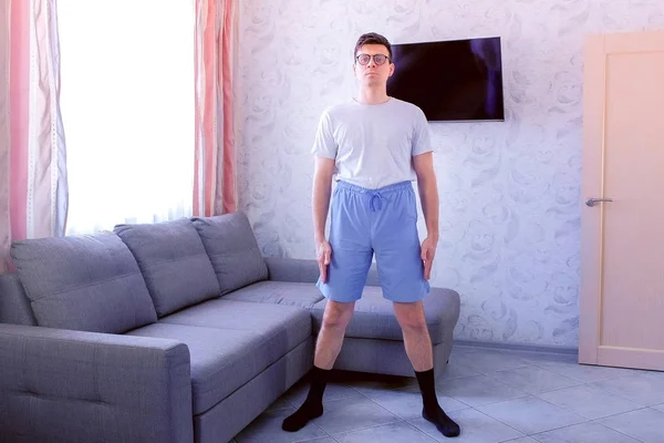 Hombre nerd divertido está haciendo ejercicios de fitness rotaciones de pelvis en casa. Concepto de humor deportivo . — Foto de Stock