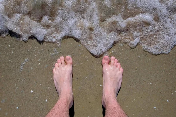 男は砂浜で barefeet 海に立っている. — ストック写真