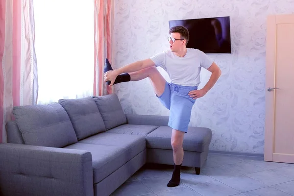 Hombre nerd divertido está haciendo pendientes hacia adelante y ejercicios de estiramiento para las piernas en casa. Concepto de humor deportivo . — Foto de Stock