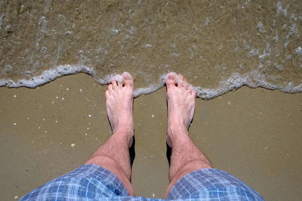 男は砂浜で barefeet 海に立っている. — ストック写真