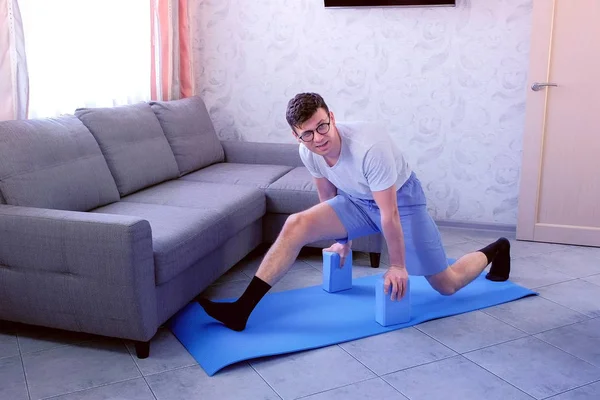 Loco empollón está tratando de hacer las divisiones la primera vez en la alfombra en casa. Concepto de humor deportivo . —  Fotos de Stock