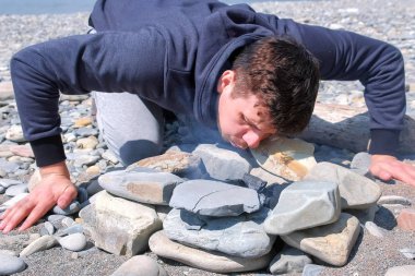 Adam taş sahilde şenlik ateşinde kömürler üzerinde esiyor. Kampüs şenlik ateşi yapma.