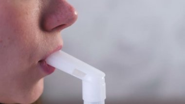 Nebulizatör ve astım tedavisi için kullanın. Genç kadın kanepede oturan boğaz için oksijen tüpü başlığı aracılığıyla teneffüs edilmesi. Yakın çekim dudak ve burun.