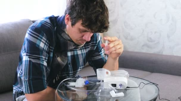 Sick man pours the saline from the syringe into the container for the inhaler. — Stock Video