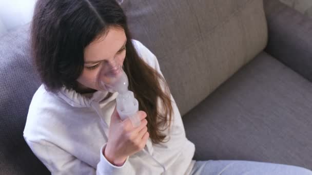 Use nebulizador e inhalador para el tratamiento. Mujer joven inhalando a través de la máscara del inhalador . — Vídeo de stock