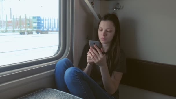 Fáradt fiatal nő, a vonat, néz video-ban mozgatható telefon.