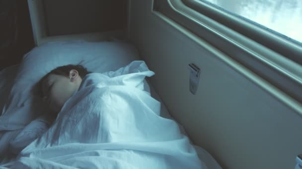 Niño está durmiendo en el coche de un tren en movimiento en la mañana temprano . — Vídeos de Stock