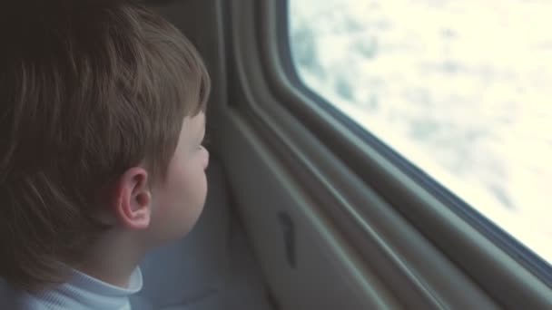 Menino está olhando na janela em movimento trem na paisagem de inverno, adormecer e deitar-se na cama . — Vídeo de Stock