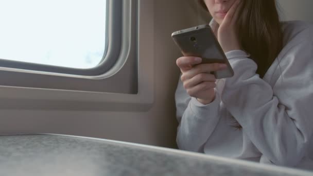 Moe jonge vrouw in trein kijken naar video in mobiele telefoon. Handen close-up. — Stockvideo