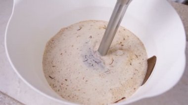 Mix blender ile sıvı koyu çikolata ve beyaz bir kase krem. Yakın çekim görünümü.