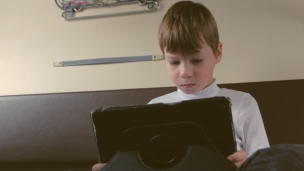 Garçon dans le train joue une tablette dans une voiture de deuxième classe — Video