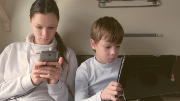 Moeder en zoon in gadgets reizen per trein is een spellen spelen in een tweederangs vervoer. — Stockvideo