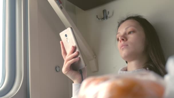 Femme fatiguée lit un livre dans un smartphone voyageant sur un train longue distance . — Video