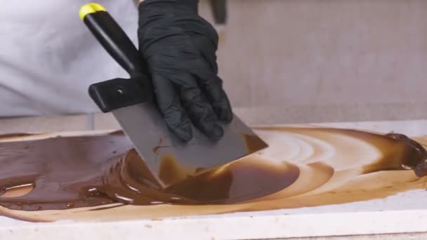 Rozpuszczanie roztopionej czekolady na naturalnym kamieniu. Damskie ręce i łopatka zbliżenie. — Wideo stockowe