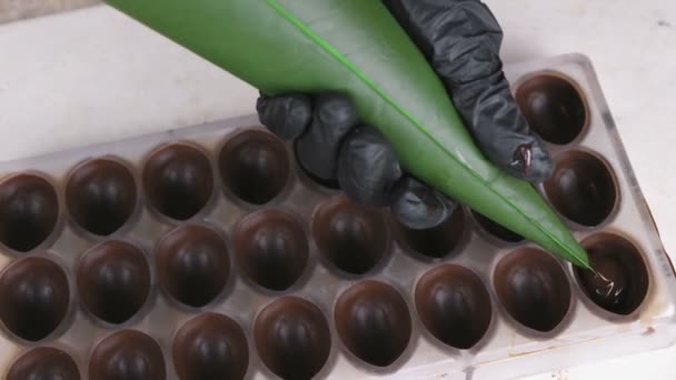 Panaderos manos vertiendo praliné de relleno de chocolate líquido en forma de bolsa de pastelería . — Vídeo de stock