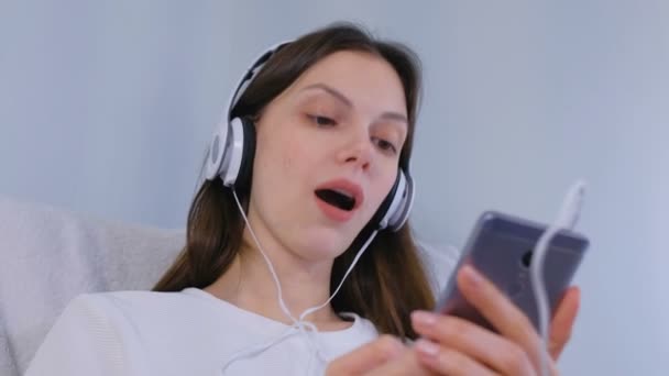 Femme écoute de la musique dans les écouteurs sur smartphone et chanter une chanson . — Video