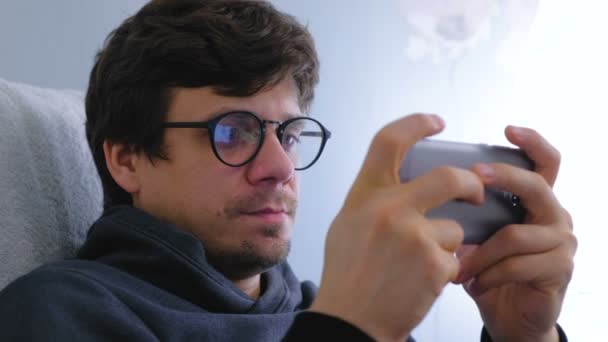 Portrait de l'homme en lunettes est de taper un message dans les médias sociaux sur smartphone . — Video