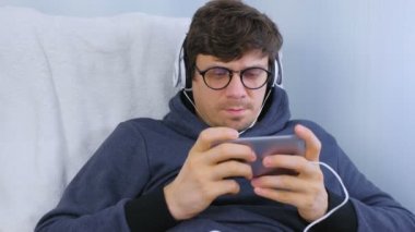Adam gözlük ve kulaklık smartphone içinde bir oyun oynuyor. Oyun sakin ol.