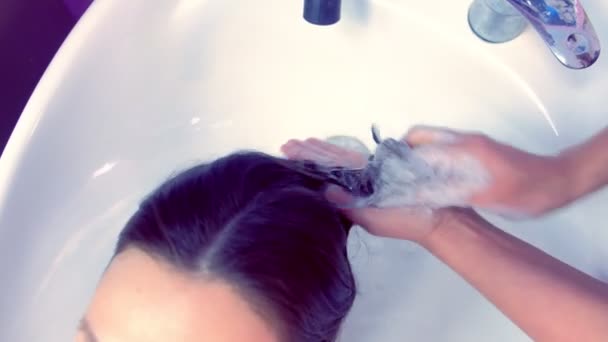 Barber washing clients hair in beauty salon in sink. — Stock Video