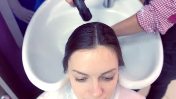 Barber washing clients hair in beauty salon in sink. — Stock Video