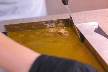 Üretim yapıştırın. El yapımı. Ellerinde eldiven hamur tabakası bir bıçak ile kesmek..