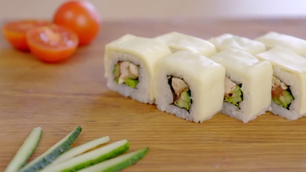 Rullar med kyckling, gurka, gröna och cream chesse ovanpå serveras på planka med grönsaker. — Stockvideo