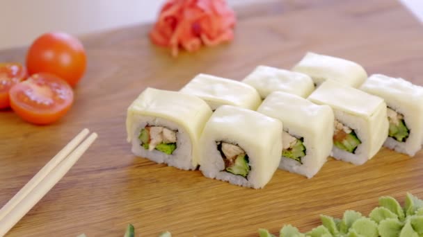 Rouleaux avec poulet, concombre, légumes verts et crème sur le plateau en bois avec wasabi, mariné, gingembre rouge, sauce soja et légumes . — Video