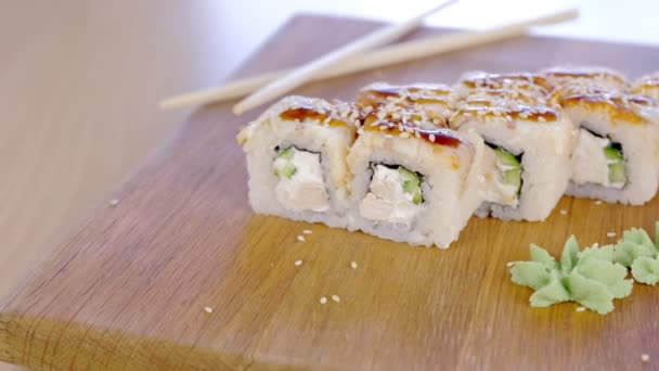 Rullar med fisk och sesam frö på toppen serveras i träskiva med wasabi, ingefära och soja sås. — Stockvideo