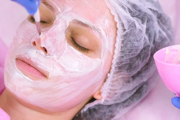 Cosmetologist puts mask on womans face with brush. Moisturizing face. Face close-up. — Stock Photo, Image