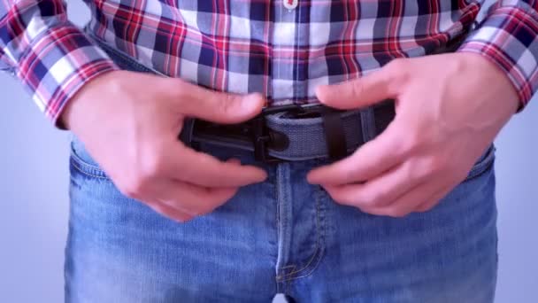 Man rechtzetten de riem op zijn jeans en vouwt zijn handen in de taille, handen close-up. — Stockvideo