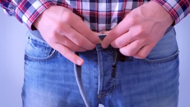 Homem está abotoando suas calças de ganga e dobrando o cinto vestindo, mãos fechadas . — Vídeo de Stock