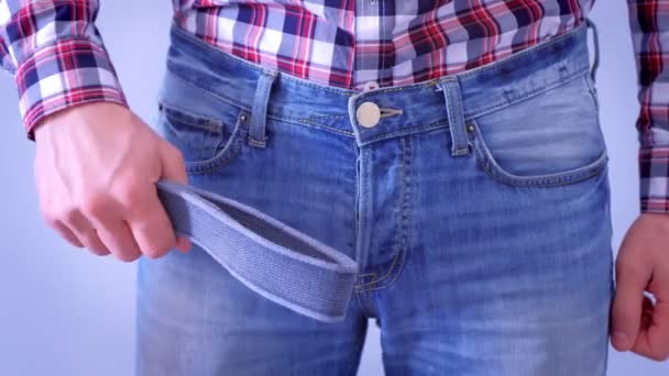 Mann in Jeans schlägt Gürtel auf den Schritt, Hände in Großaufnahme. Verspielte Sex-Stimmung.