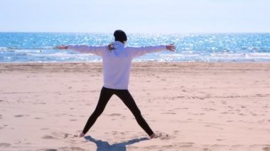 Kadın acemi üçgen yoga poz kum deniz plaj sporu egzersiz geri görünümü yok.