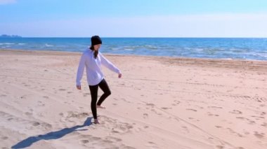 Kadın denge yoga bacaklarını ısınıyor deniz kum plajda pozlar, yan görünüm.