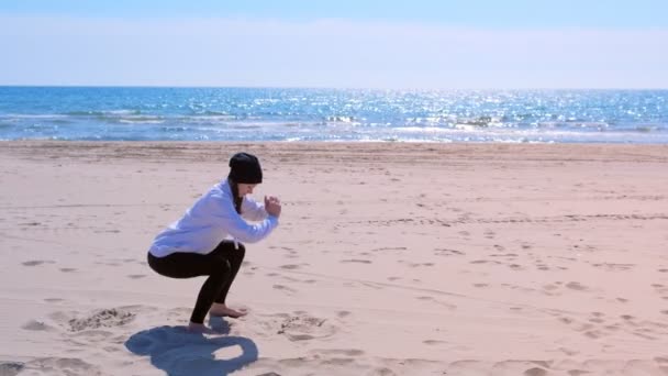 Mujer hace sentadillas en la playa de arena de mar fitness al aire libre ejercicios deportivos de entrenamiento . — Vídeos de Stock