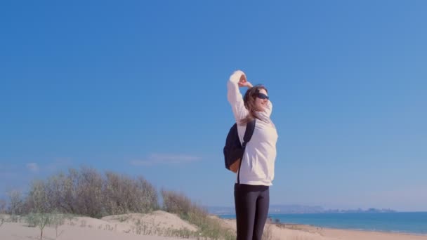 Mujer feliz levanta los brazos en la parte superior de la duna de arena en el mar concepto ganador playa . — Vídeo de stock