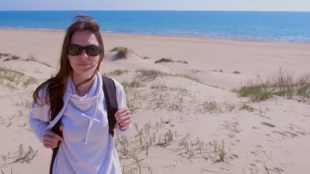 Chica viajero con mochila está mirando alrededor en la playa de arena de mar de vacaciones . — Vídeo de stock