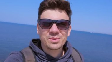 Güneş gözlüğü selfie kamera adam blogger gezgin denizde tatil hakkında konuşuyor.