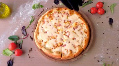 Şef serpin pastırma pizza peyniri rendesi. Elinde lastik eldiven, üstten görünüm.