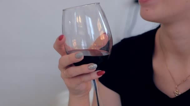 彼女の手に赤ワインのグラスを持つ女性はワインを飲みます. — ストック動画