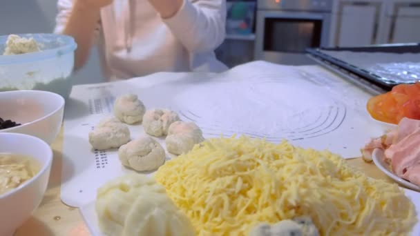 Mujer hace bolas de masa para pizza con diferentes ingredientes. Primer plano de las manos . — Vídeos de Stock